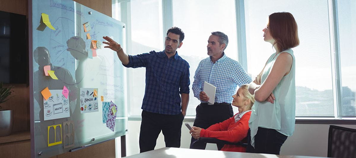 Photo of people standing in front of whiteboard